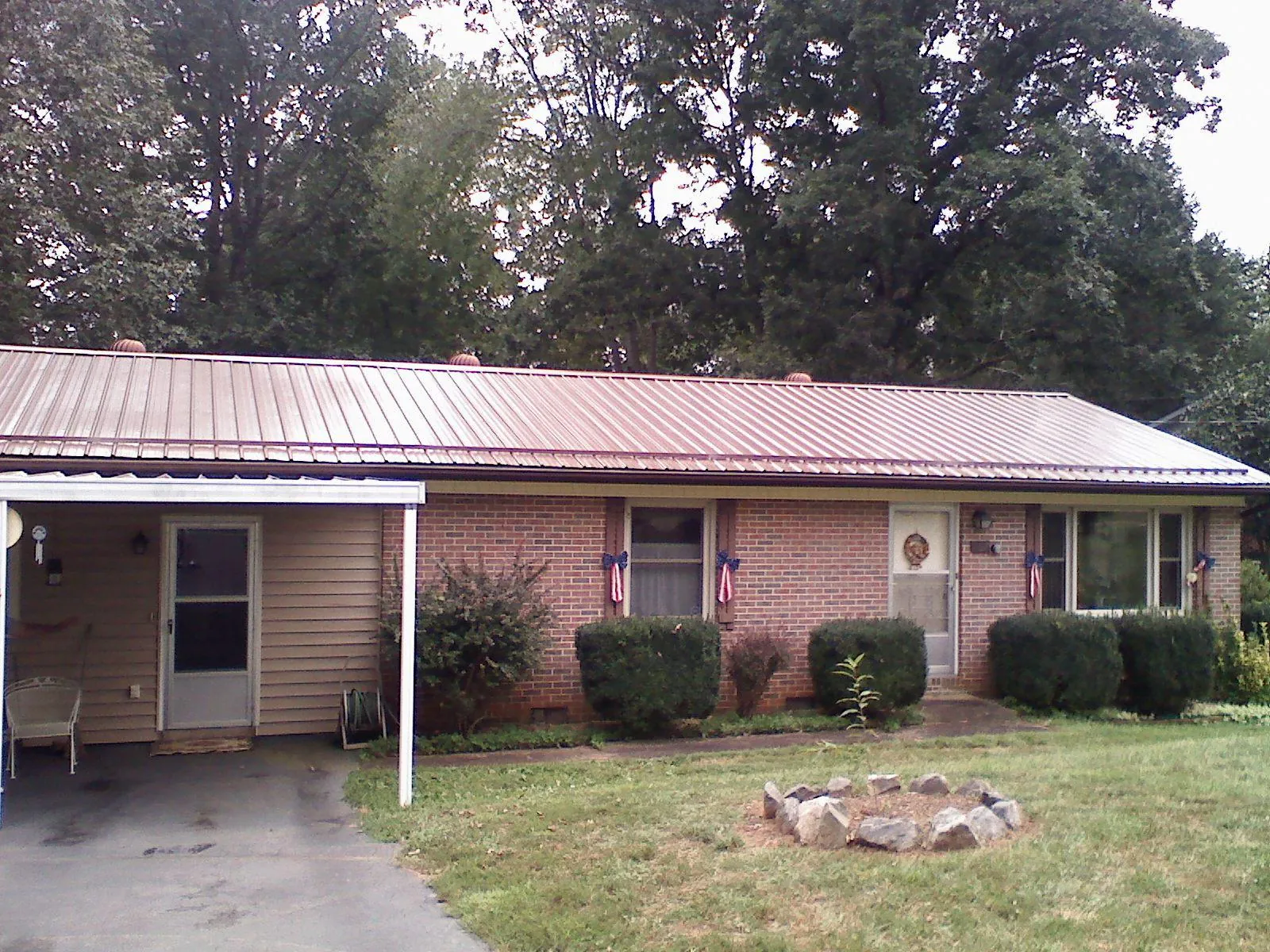 Bronze metal roof and carport on a brick ranch home — Roof Repair work by our crew in Wellston