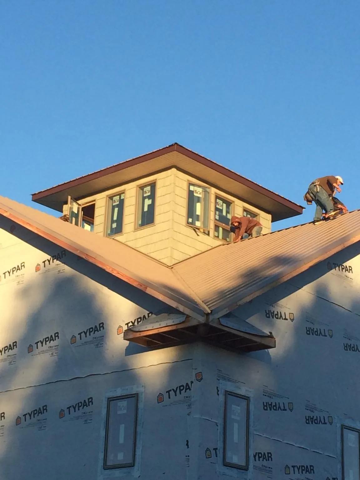 Roofers working around a rooftop cupola on a new metal roof at sunset — Roof Waterproofing in Wellston by Roofing Brothers